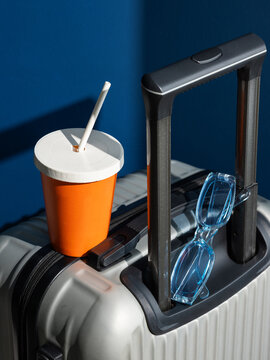 Travel Essentials On Suitcase over dark blue background