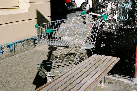 Shopping Cart by a Bench in Urban Setting