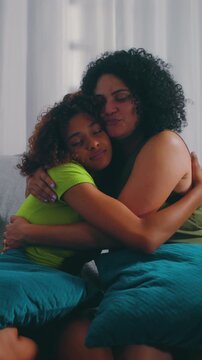 Caring Hispanic mother hugging adolescent daughter in comforting embrace at home