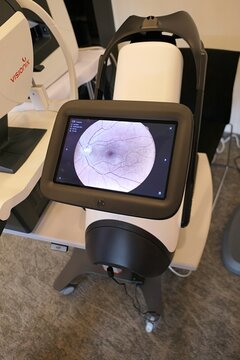 Examiner side with large touchscreen with retina scan on modern AI enhanced fundus imaging system iCare DRS Plus, with large touchscreen, displayed on medical expo. Visionix VX 120 in background. 