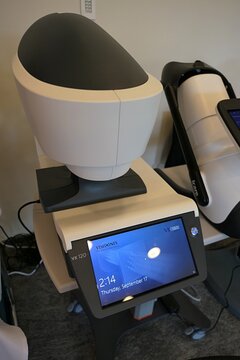 Touchscreen and doctor side of modern multi-purpose ophtalmology diagnostic device Visionix VX 120 Plus, displayed on expo next to modern AI powered fundus camera DRSPlus by CenterVue. 