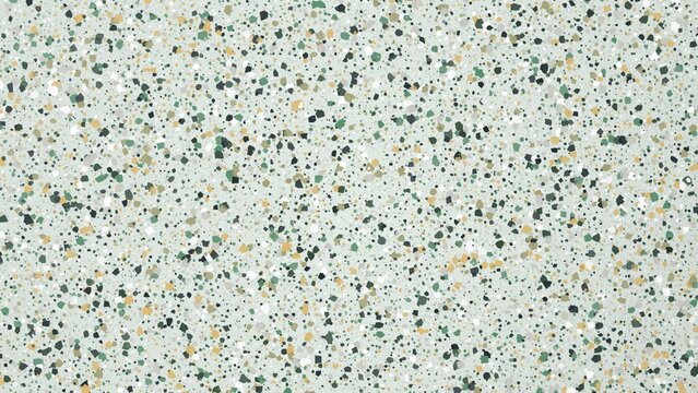 Terrazzo flooring texture with scattered green and yellow stone fragments light surface.
