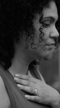 Close-up of pensive middle-aged woman touching chest in emotional distress in black and white