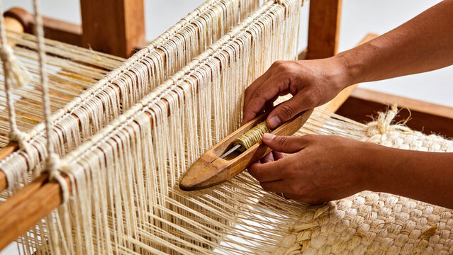 Artisan hands skillfully weaving eco friendly banana fiber fabric on traditional wooden loom for sustainable textile design