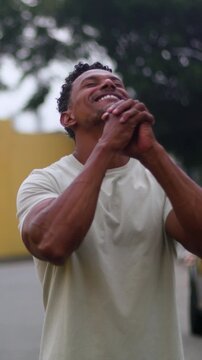 Man of African descent clasping hands with eyes uplifted in outdoor spiritual prayer