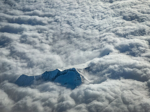 Aerial view of the snow-capped peaks of the Mont Blanc massif rising above a thick layer of clouds in the French Alps, Chamonix, Auvergne-Rhone-Alpes, France.