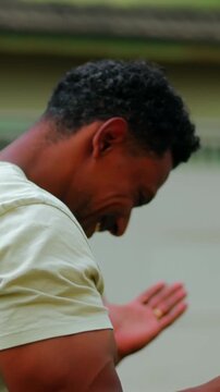 African American man with closed eyes pressing hands together in humble outdoor prayer