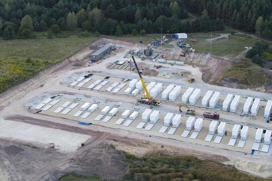 Aerial view of BESS storage facility under construction with rows of battery containers, a mobile crane, and construction equipment in Trzebinia, Lesser Poland Voivode, Poland.