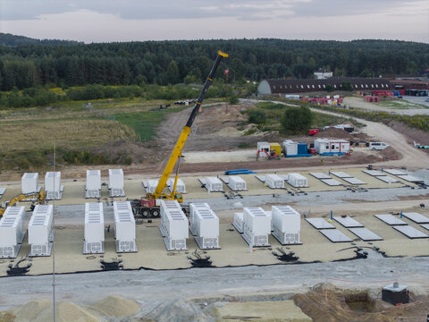 Aerial view of the BESS battery energy storage system construction site featuring rows of white containers and a mobile crane in Trzebinia, Lesser Poland Voivode, Poland.