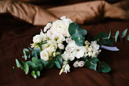 Bridal Bouquet of White Roses and Eucalyptus on Brown Fabric Background