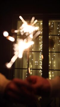 Hands Holding Glowing Sparklers against golden lights bokeh at night, Vertical Close Up. Holiday Celebration Cheer video. Happy new year