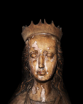 Late gothic wooden carved bust of a female saint wearing a crown isolated on black background