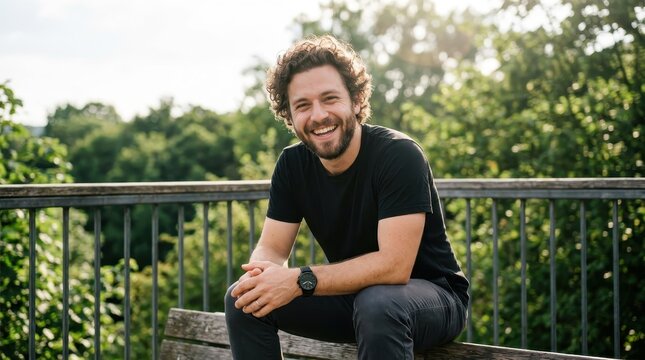 Portrait of a Happy Young Man with Curly Hair and Beard Smiling Outdoors in a Park