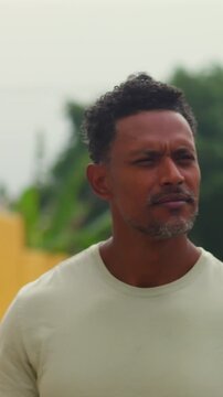 African American man walking along urban street with thoughtful expression near yellow wall