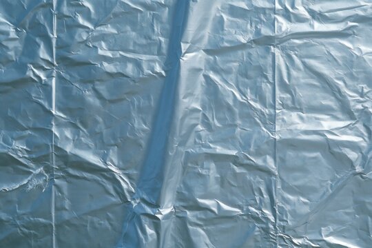 Crumpled kitchen foil with a creased and frosted metallic surface, featuring soft lavender and periwinkle tones for background design assets