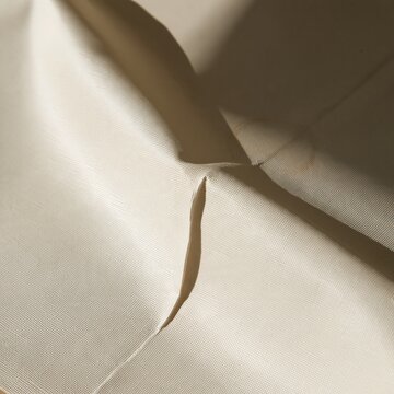 Cream oilcloth surface with a soft crease and water ring, featuring a matte woven texture for retirement income and budget backgrounds