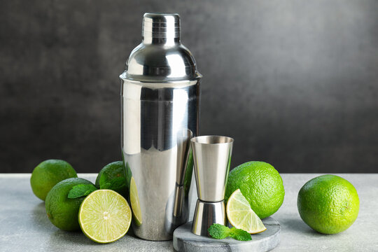 Ingredients for mojito, shaker and jigger on light grey table. Space for text