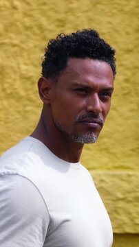 Side profile of African American man walking along yellow wall in thoughtful contemplation