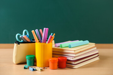 Different stationery on wooden table near chalkboard, closeup © New Africa