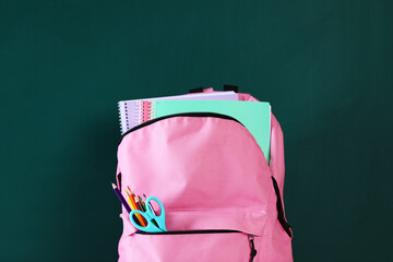 Backpack with notebooks and stationery against chalkboard, closeup © New Africa