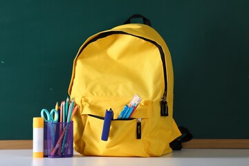 Backpack with stationery on white desk against chalkboard © New Africa