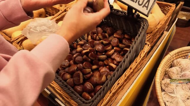 Video showing shoppers selecting fresh chestnuts by hand from a basket at an indoor market