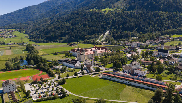Aerial view of Stift Stams monastery with its distinctive red roofs surrounded by lush green fields and mountains in Stams, Tirol, Austria.