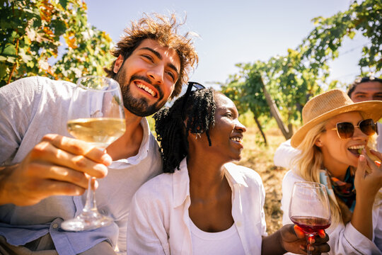 Friends toasting with wine while relaxing among vineyard grapes