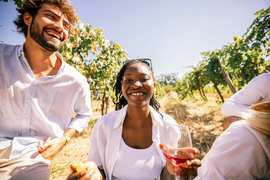 Friends drinking wine together in a vineyard on a sunny day