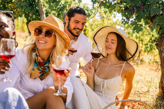 Friends laughing and drinking wine together in a vineyard