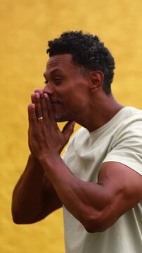 African American man standing with hands pressed together in quiet faith and humble gratitude