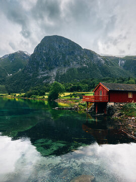Lake and mountains with red wooden house by the water in Norway peaceful scenery nordic summer landscape rural scenic nature view, summer season in More og Romsdal travel destinations in Scandinavia