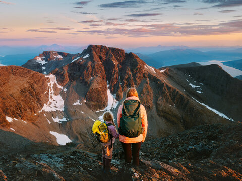 Family spending active vacations in mountains mother and child hiking together with backpacks gear in Norway, travel autumn holidays parent and kid in Lyngen Alps adventure tour outdoor