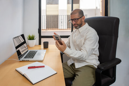 Man looking at smartphone with confused expression in office