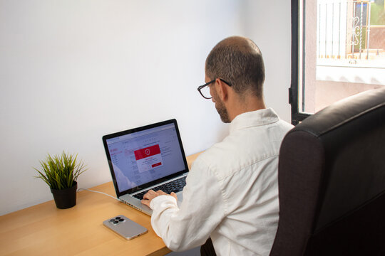 Man looking at laptop with email security alert in office