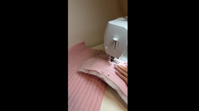 Close-up footage of quilted fabric being stitched on a sewing machine. Detailed view of quilting, fabric layers and needle movement during a textile and sewing project. Vertical video.