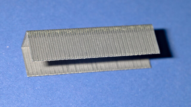 Close-up of a strip of metal staples on a blue background.