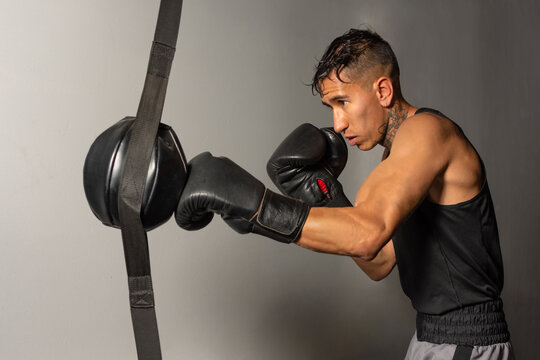 Hispanic boxer hitting speed bag against gray background