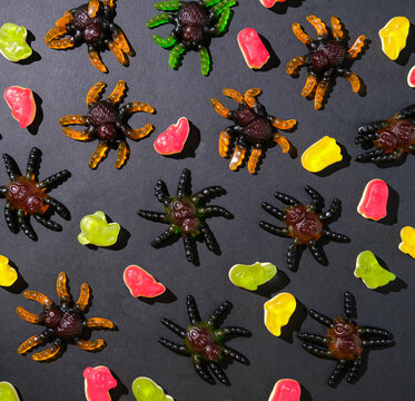 bright gummy jelly. Marmalade spiders and ghosts on black background for Halloween decoration