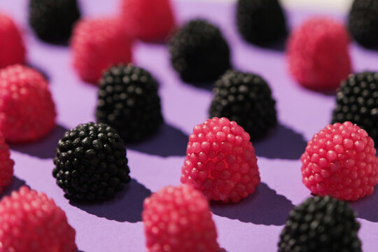 Assorted gummy candies shaped like berries top view on purple background