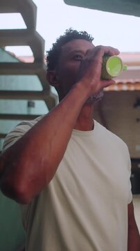 African American man holding green mug in courtyard with pensive look in casual patio setting