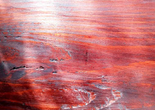Lacquered cedar wood texture with deep red grain patterns and natural weathering cracks perfect for rustic cottage interiors and warm timber panel background designs.