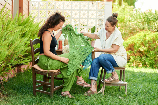 Female artisans discussing handmade crochet textile art outdoors