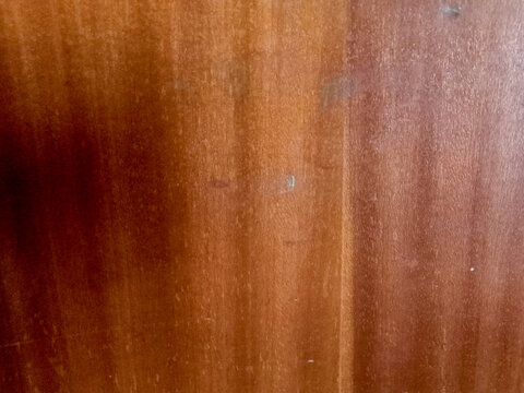 Polished brown mahogany wood veneer texture displays vertical grain lines for high end cabinetry design and elegant classic furniture manufacturing.