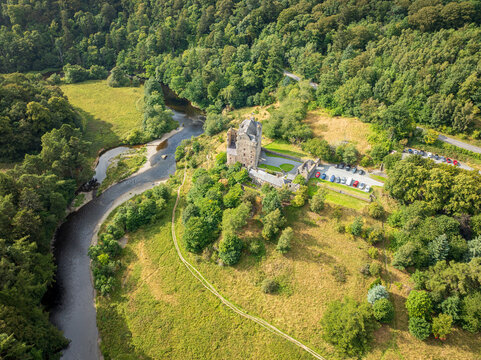 Aerial view of Neidpath Castle surrounded by lush green forests and the River Tweed in Peebles, Scotland, United Kingdom.