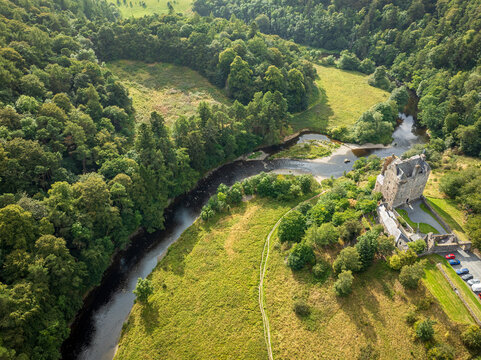 Aerial view of Neidpath Castle situated along the River Tweed surrounded by lush green forests and rolling hills in Peebles, Scotland, United Kingdom.