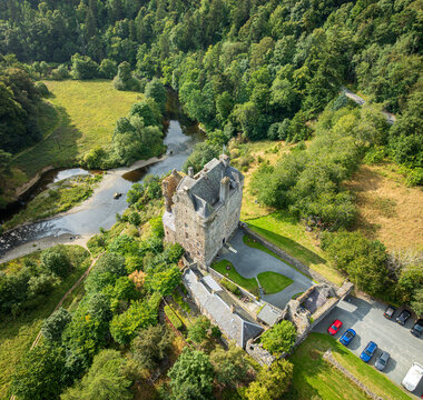 Aerial view of Neidpath Castle situated by the River Tweed, surrounded by lush green forests and rolling hills in Peebles, Scotland, United Kingdom.