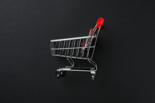 Small silver shopping cart on black background, top view