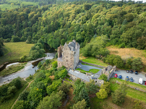 Aerial view of Neidpath Castle situated on the banks of the River Tweed, surrounded by dense woodland and green hills in Peebles, Scotland, United Kingdom.