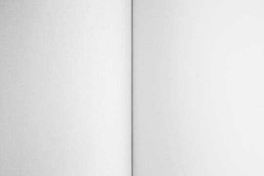 Open blank white book with clean pages and central binding, minimalist paper background with soft texture.